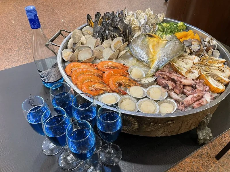 龍福山莊海鮮痛風鍋，大鍋內鋪滿蛤蜊、白蝦、透抽與鮮魚，旁邊是倒好的藍眼淚葡萄酒。